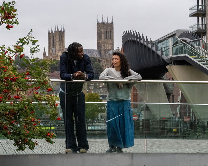 Two students chatting while on a bridge in front of Lincoln Cathedral