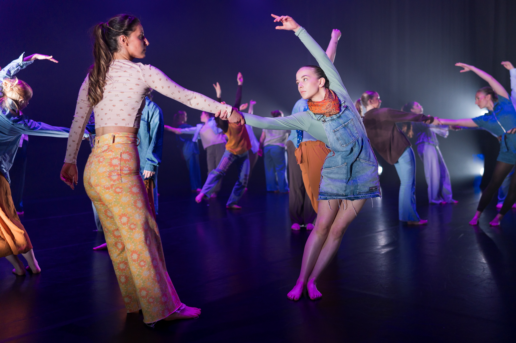 Two dancers hold hands as they perform.