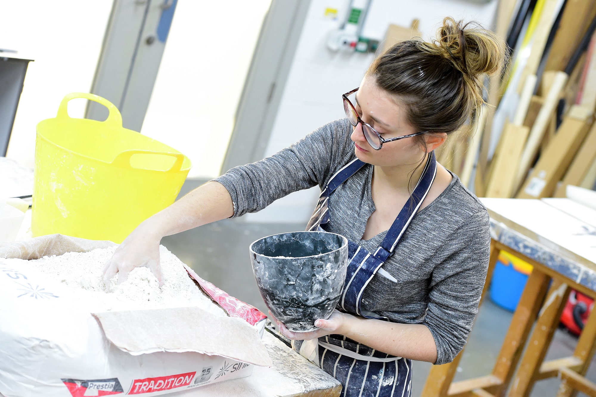 A student reaching into a bag of plaster to create a sculpture