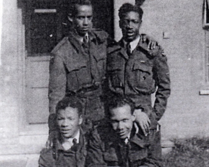 Four royal air force volunteers stood together outside a doorway during the Second World War