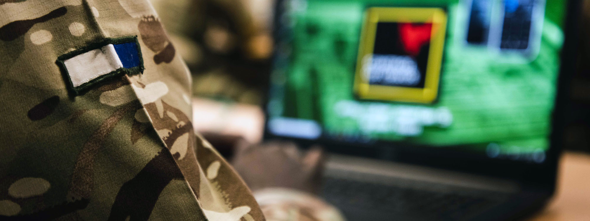A cropped image of a soldier looking at a laptop screen
