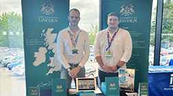 Staff standing at a Lincoln HE fair event stand.